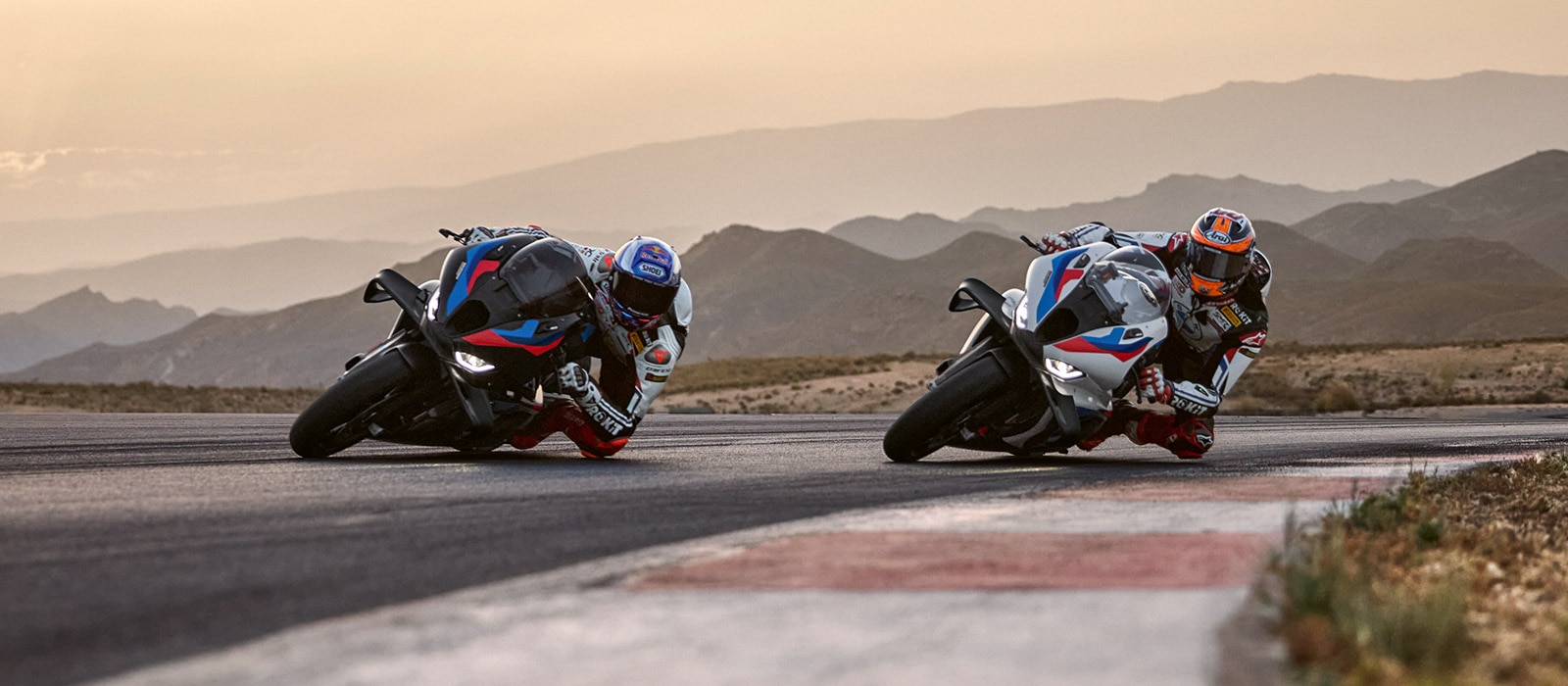 레이싱 트랙에서 최대 경사 상태로 주행하는 BMW S 1000 RR 두 대의 사진